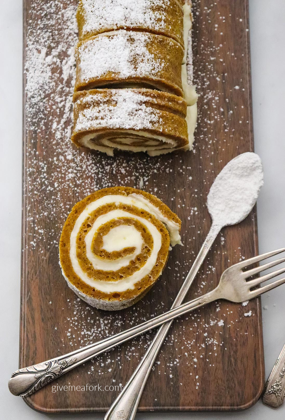 pumpkin roll on a wooden board with a fork and spoon