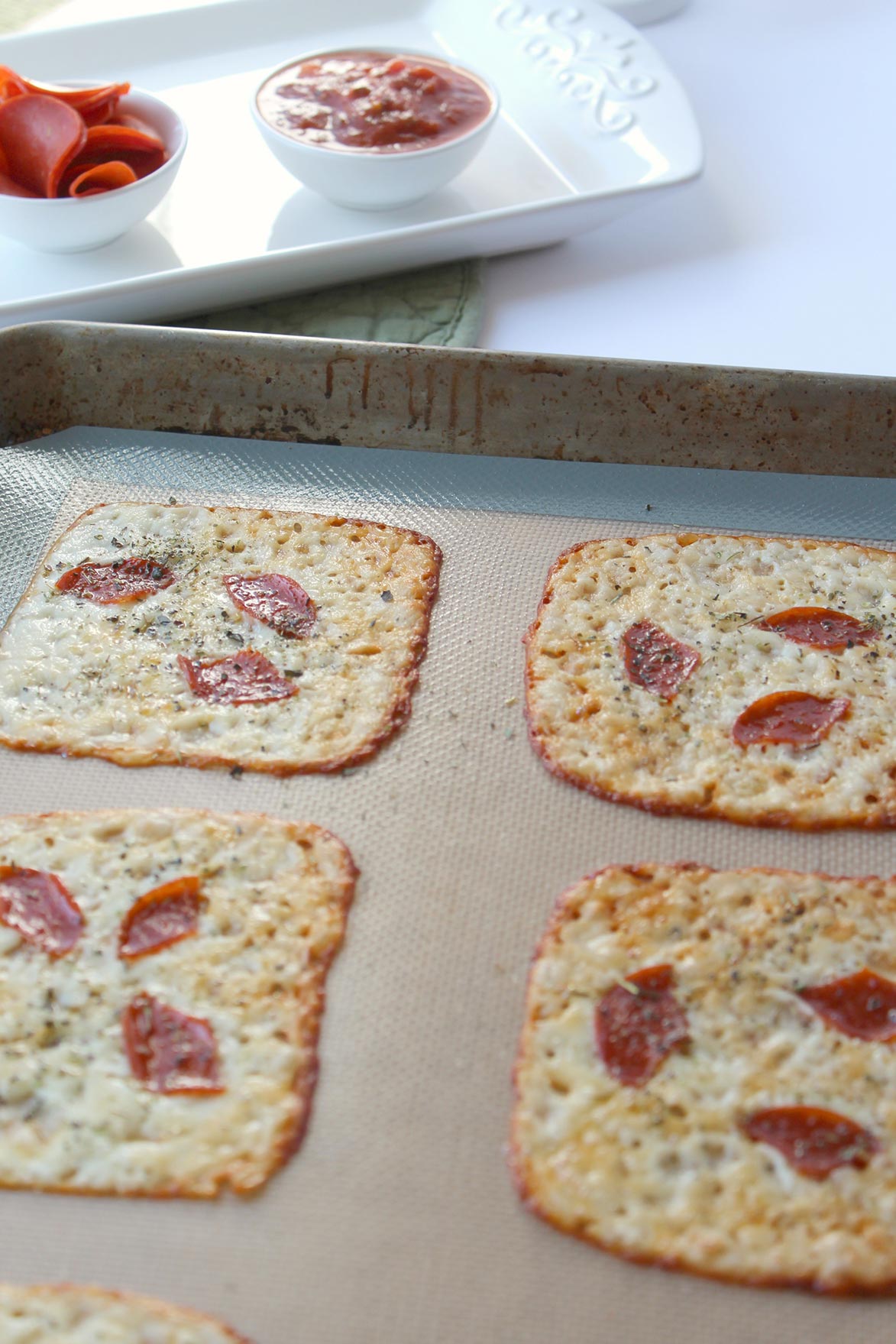 four slices of melted cheese with pepperoni on a baking sheet 