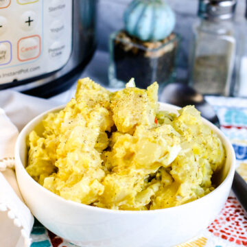 potato salad in a small white bowl with an instant pot and salt shakers in the background.