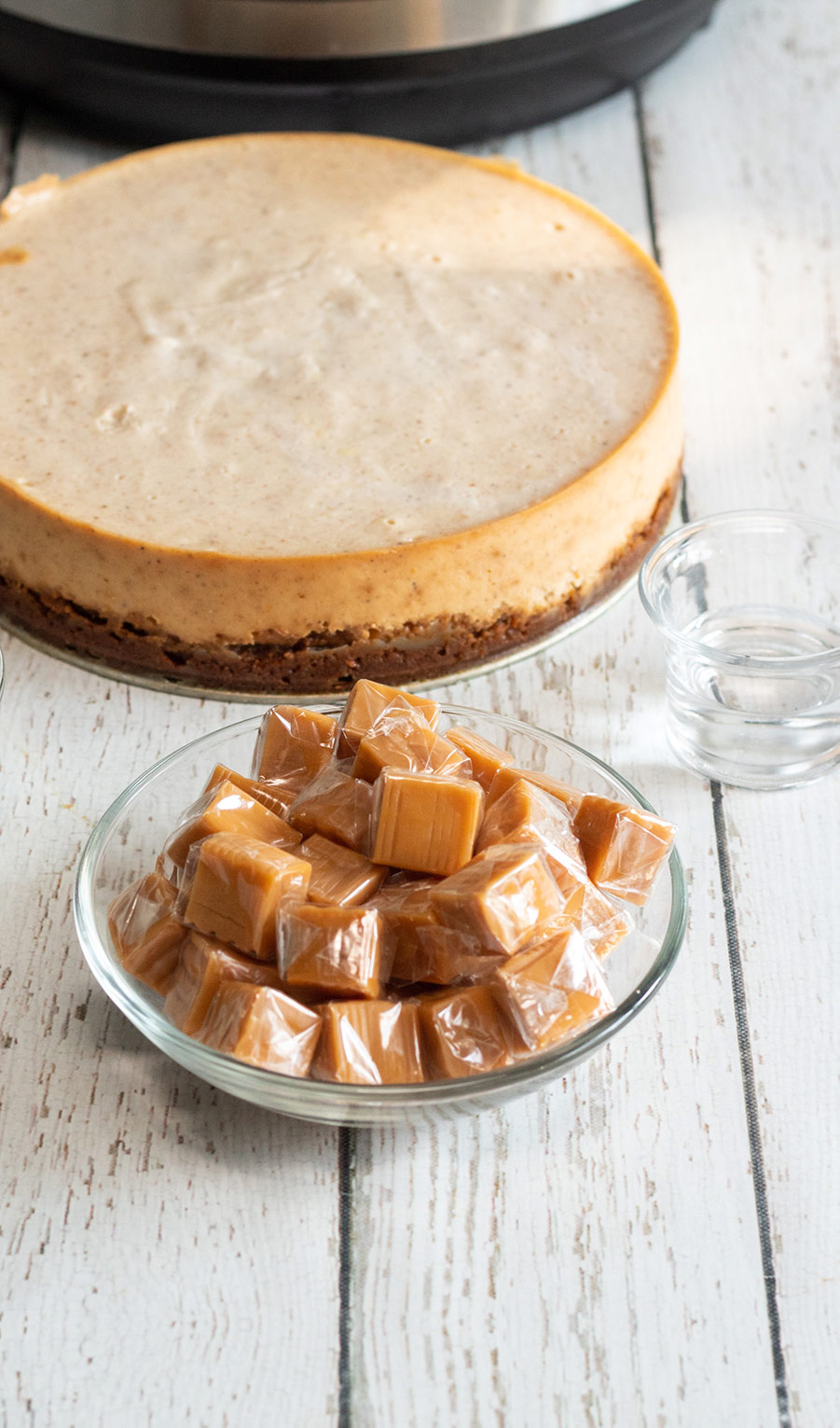 eggnog cheesecake in the background and a bowl of caramel candies up front. 