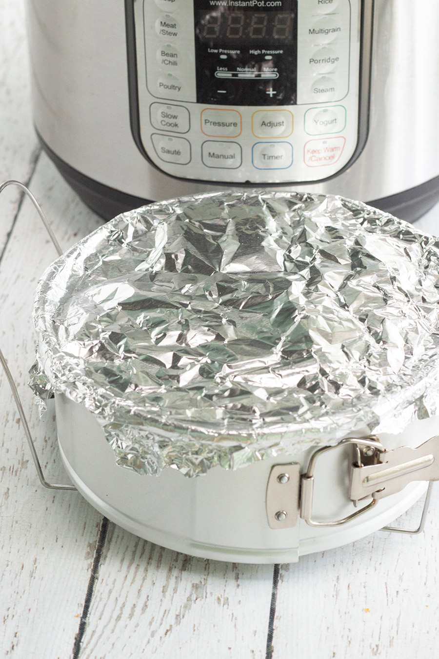 springform pan covered with aluminum foil and an instant pot in the background. 