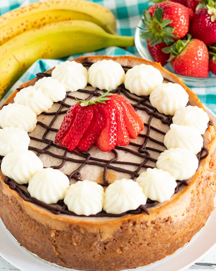 instant pot banana split cheesecake with strawberries and bananas in the background.