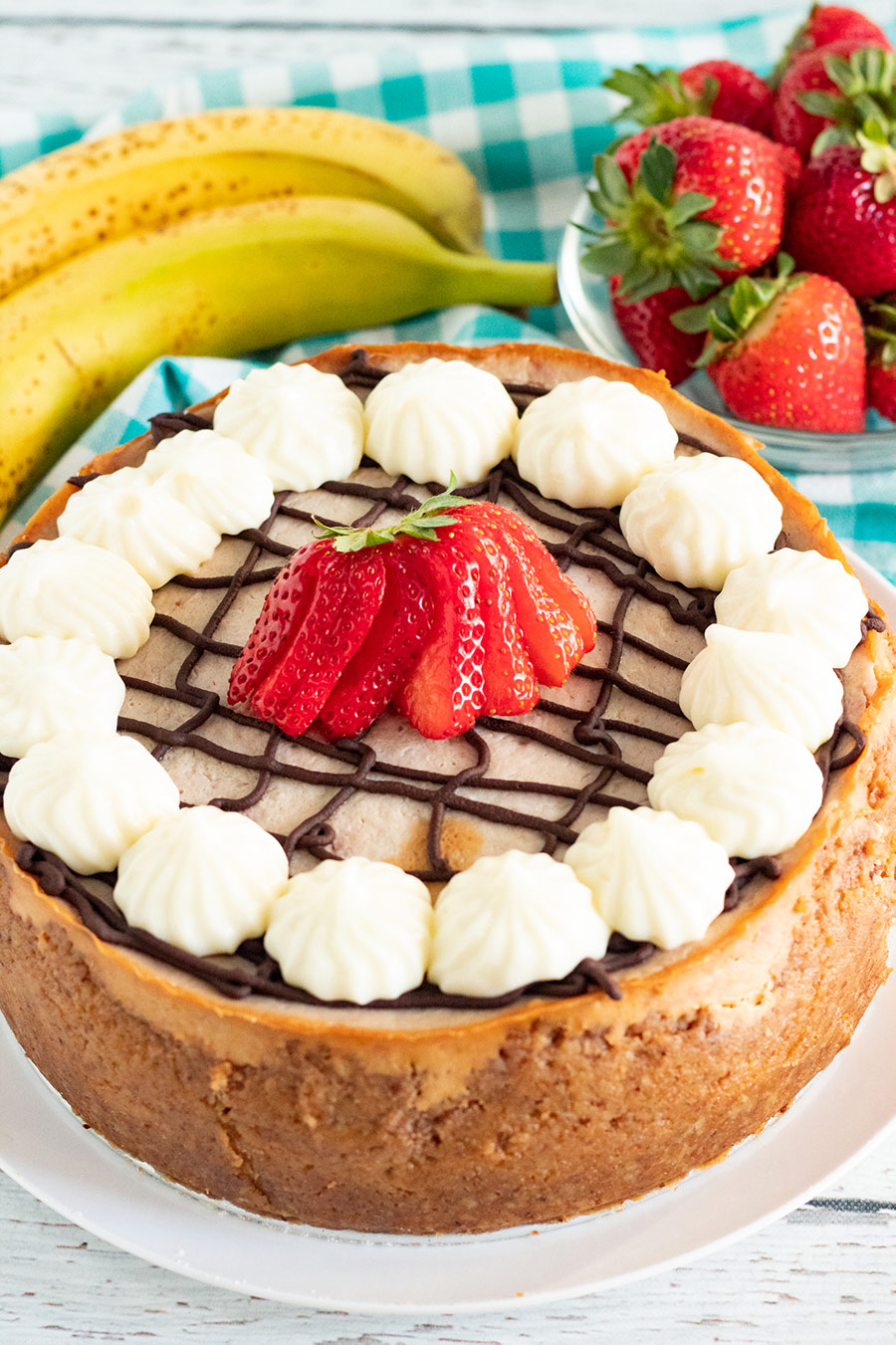 instant pot banana split cheesecake with strawberries and bananas in the background.