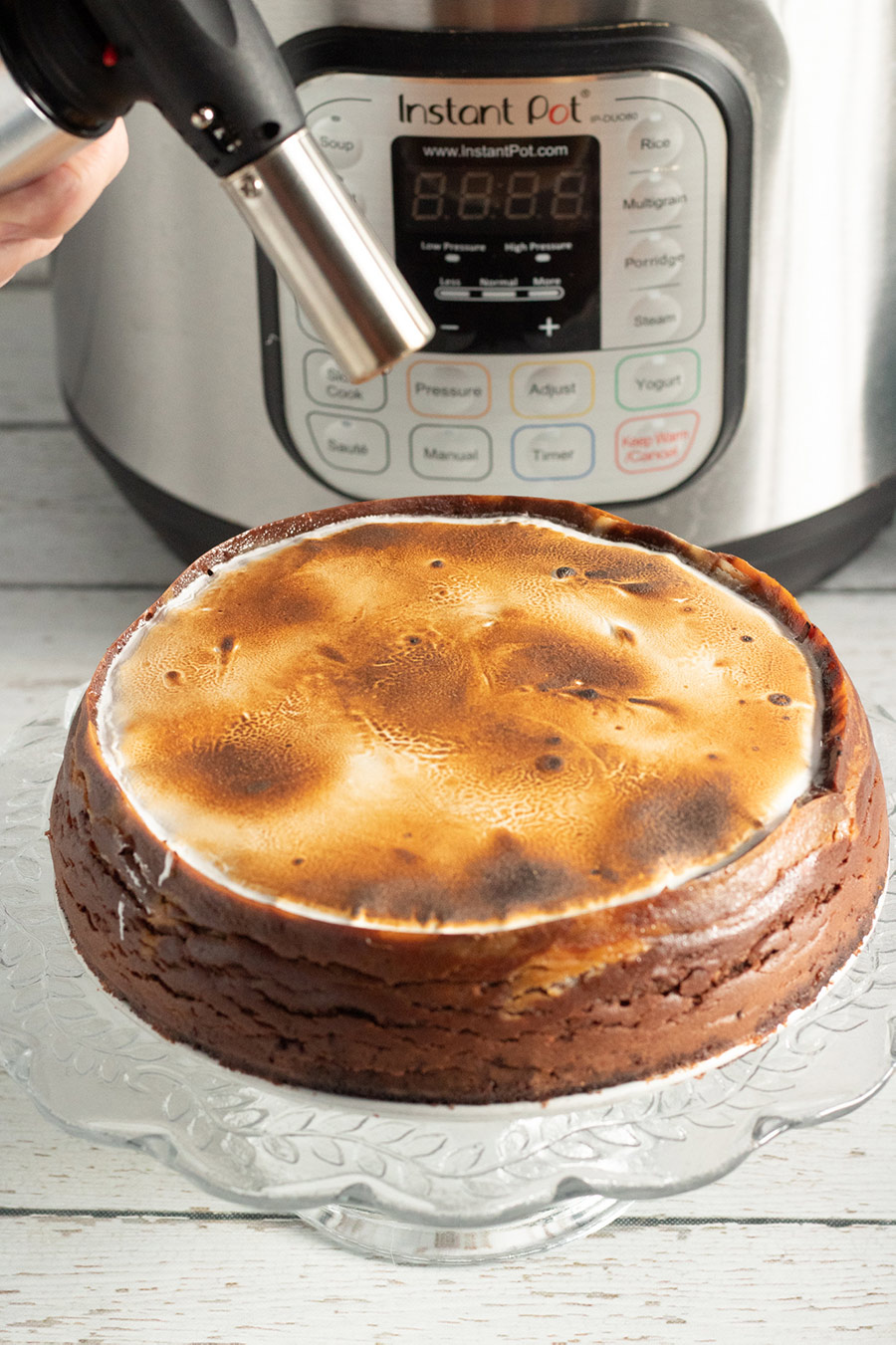 a kitchen torch, a cheesecake, and an instant pot in the background. 