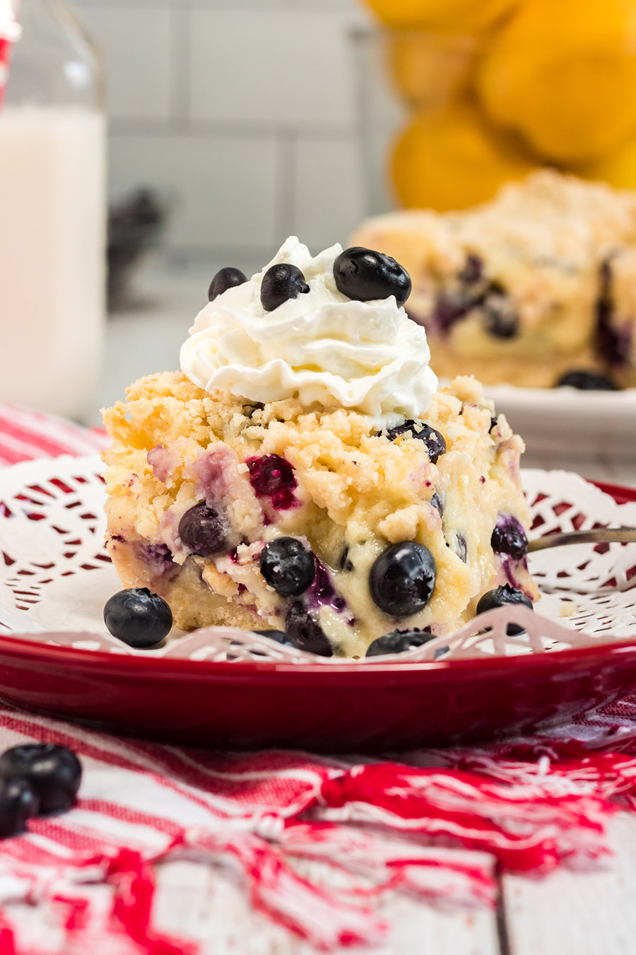 a slice of blueberry cake with whipped cream on a plate. 