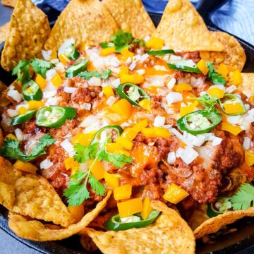 ground beef nachos with cheese and peppers on top.