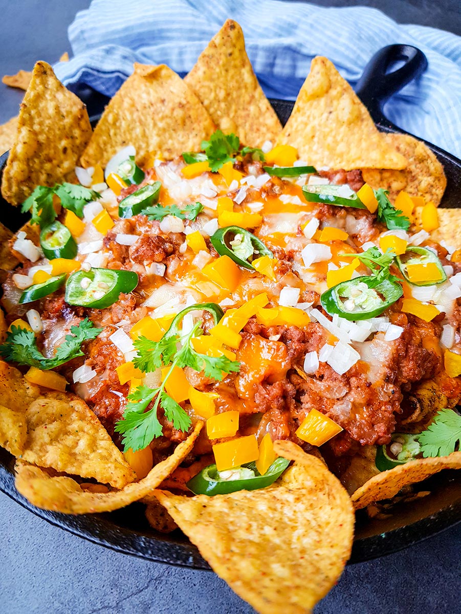 ground beef nachos with cheese and peppers on top. 