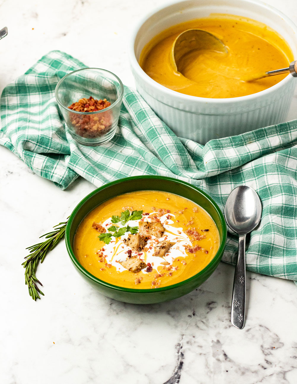 butternut squash soup in a green bowl with cream and bacon on top. 