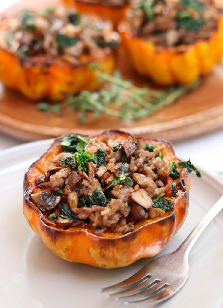 acorn squash filled with kale and sausage on a white plate with a fork. 