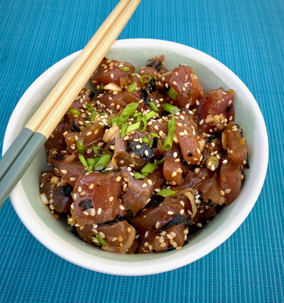 ahi poke in a white bowl with chop sticks. 