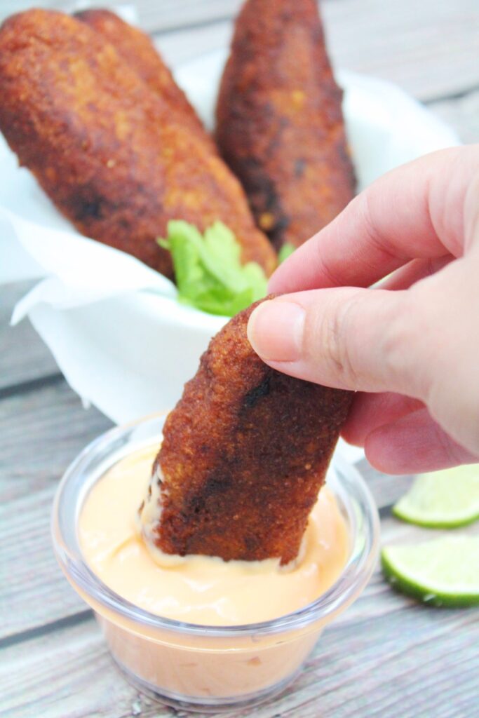 alcapurrias dipped in sauce.