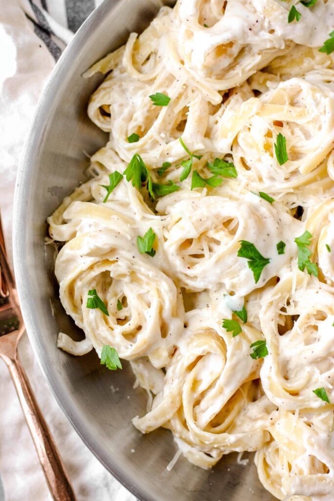 fettuccine alfredo in a skillet up close.