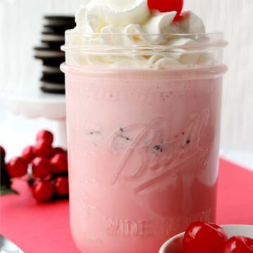 pink strawberry oreo milkshake with whipped cream and a cherry on top.