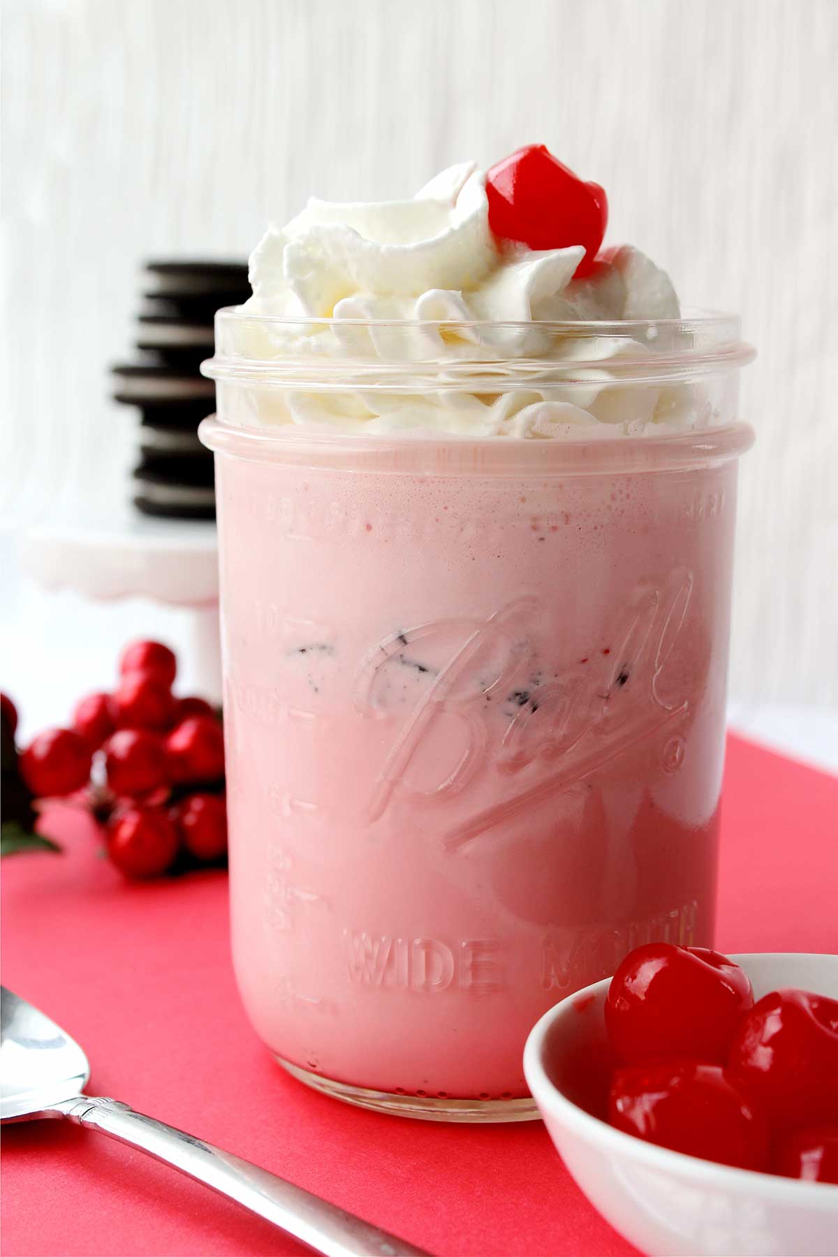 Pink strawberry oreo milkshake with whipped cream and a cherry on top. 