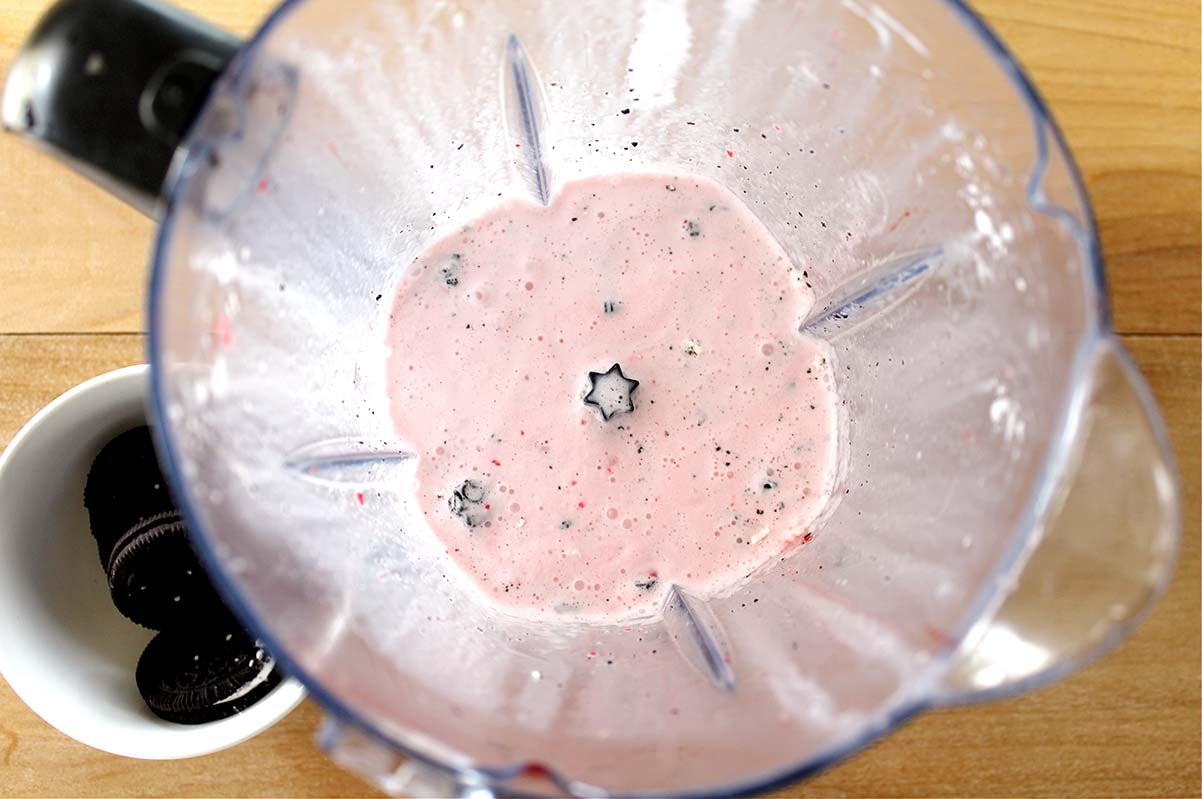 milkshake in a blender with Oreo cookies on the side.