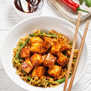 tofu and ramen in a white bowl with chopsticks.