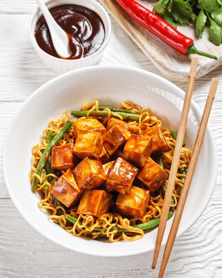 tofu and ramen in a white bowl with chopsticks.