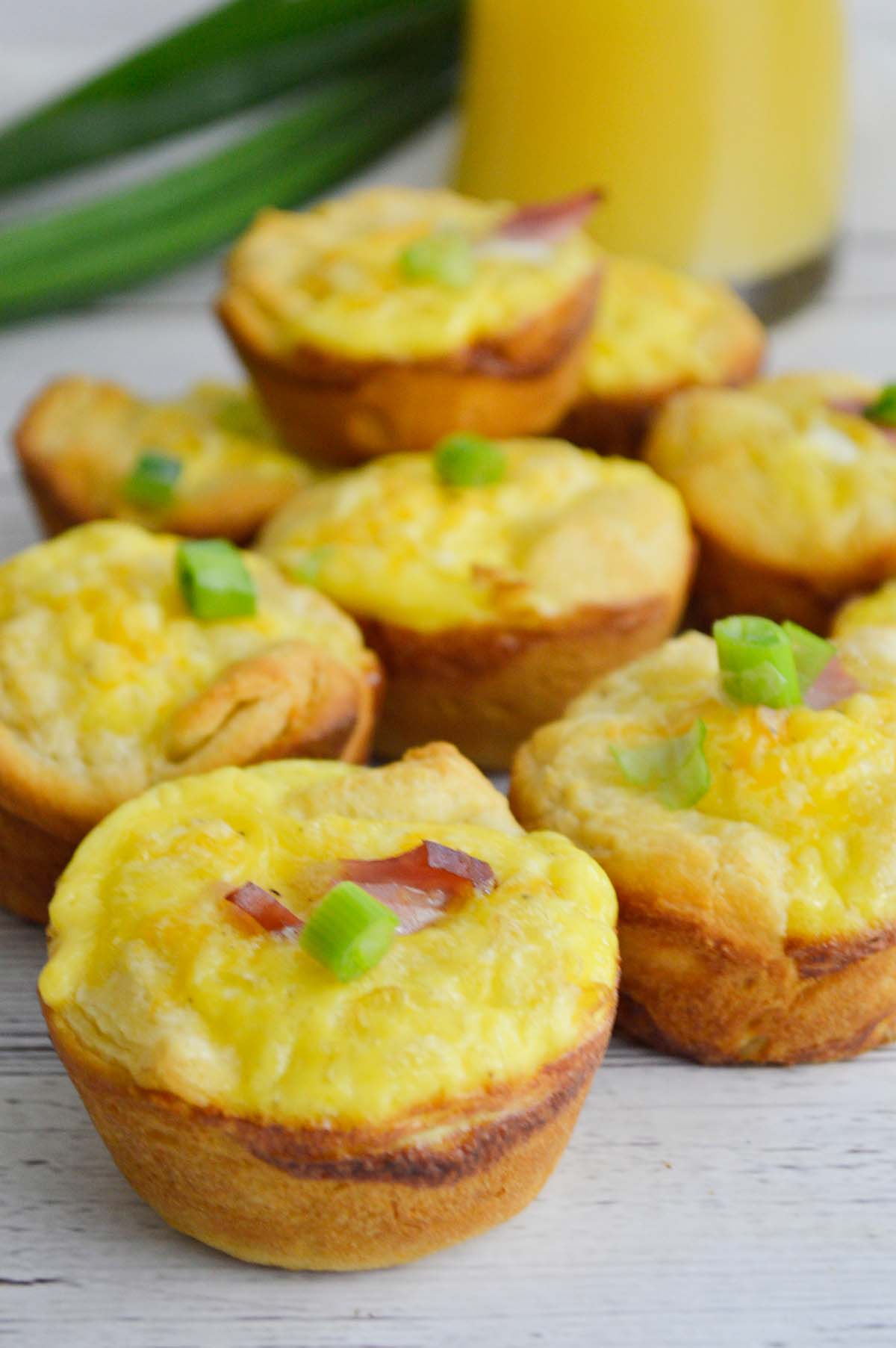 ham and cheese egg cups with orange juice and scallions in the background. 