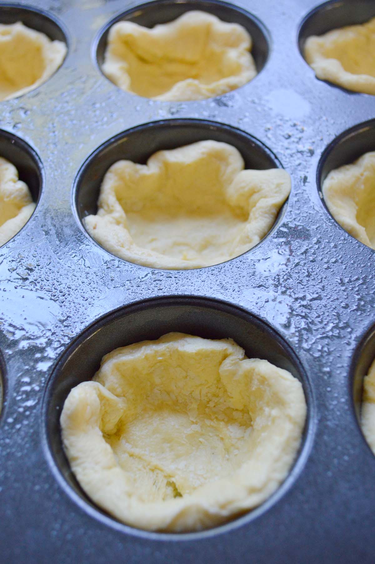 raw biscuit dough in muffin tin.