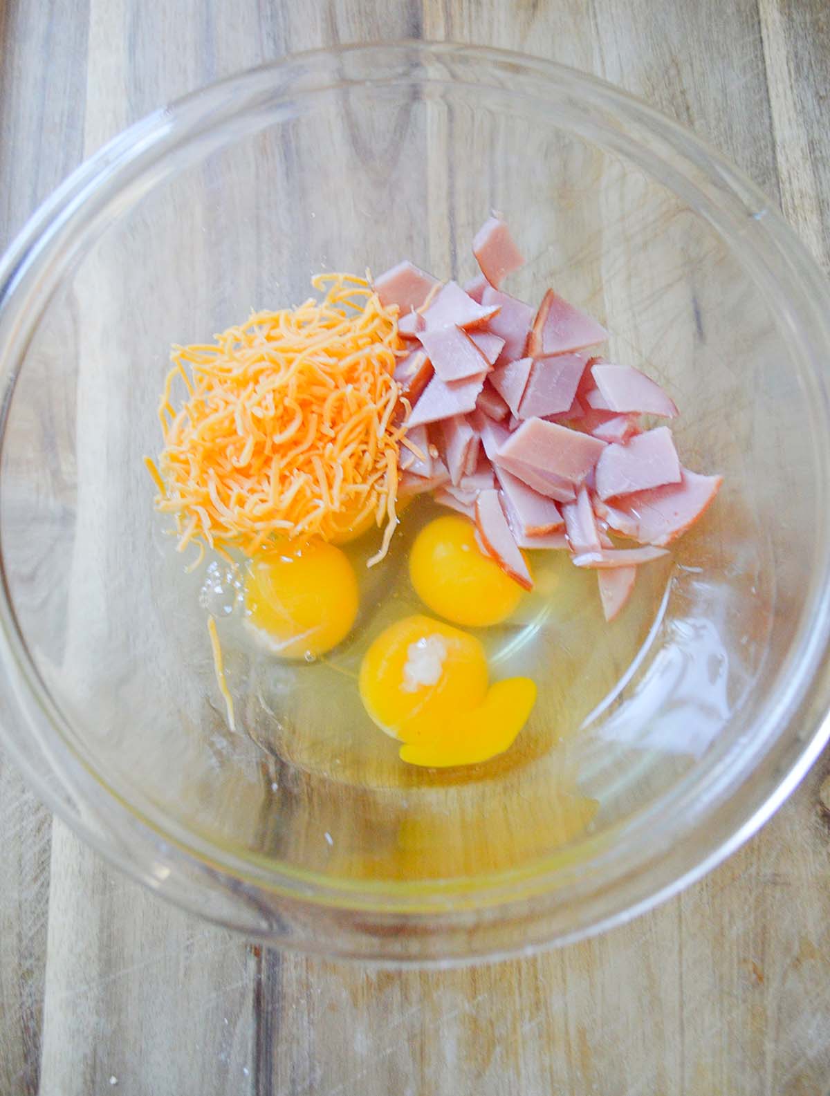 eggs, ham, and cheese in a glass bowl.