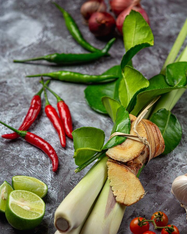 Thai basil with limes, tomatoes, and red chilies on the side.