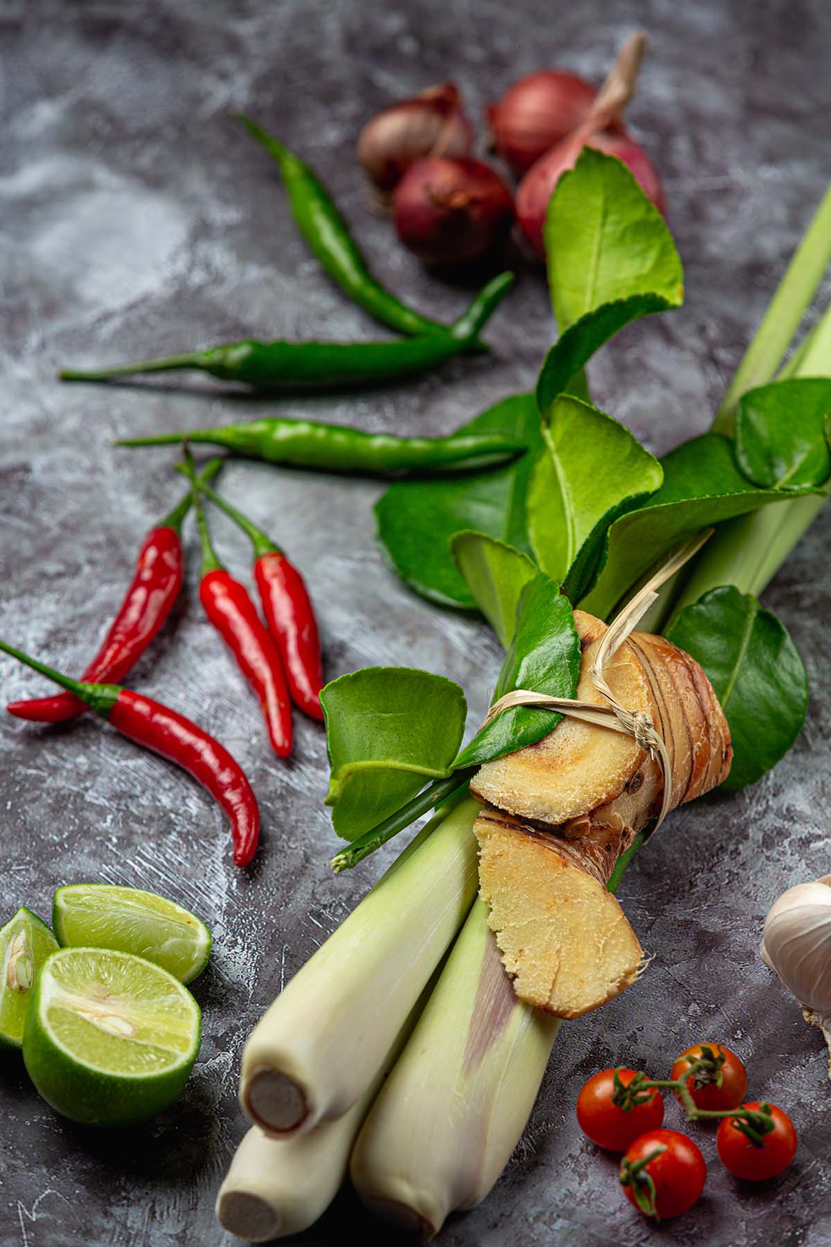 Thai basil with limes, tomatoes, and red chilies on the side.
