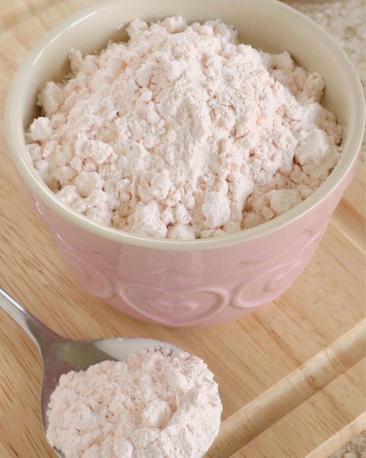 Custard powder in a pink bowl and on a spoon.