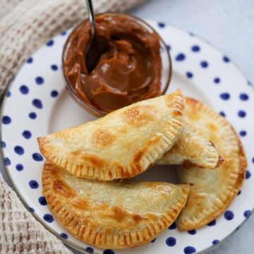 dulce de leche empanadas on a plate with dulce de leche on the side.