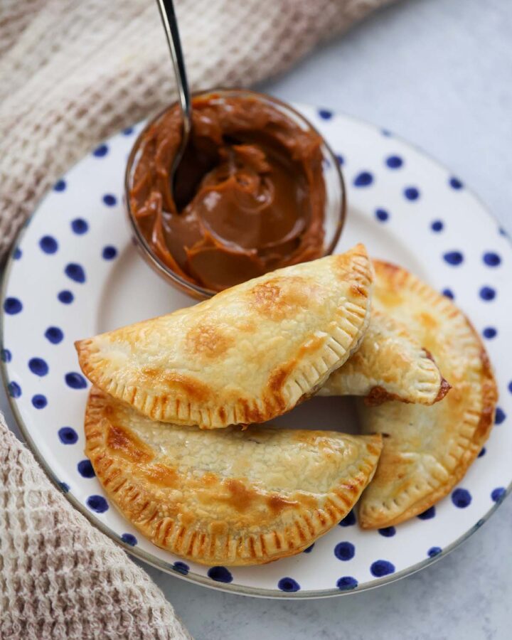 dulce de leche empanadas on a plate with dulce de leche on the side.