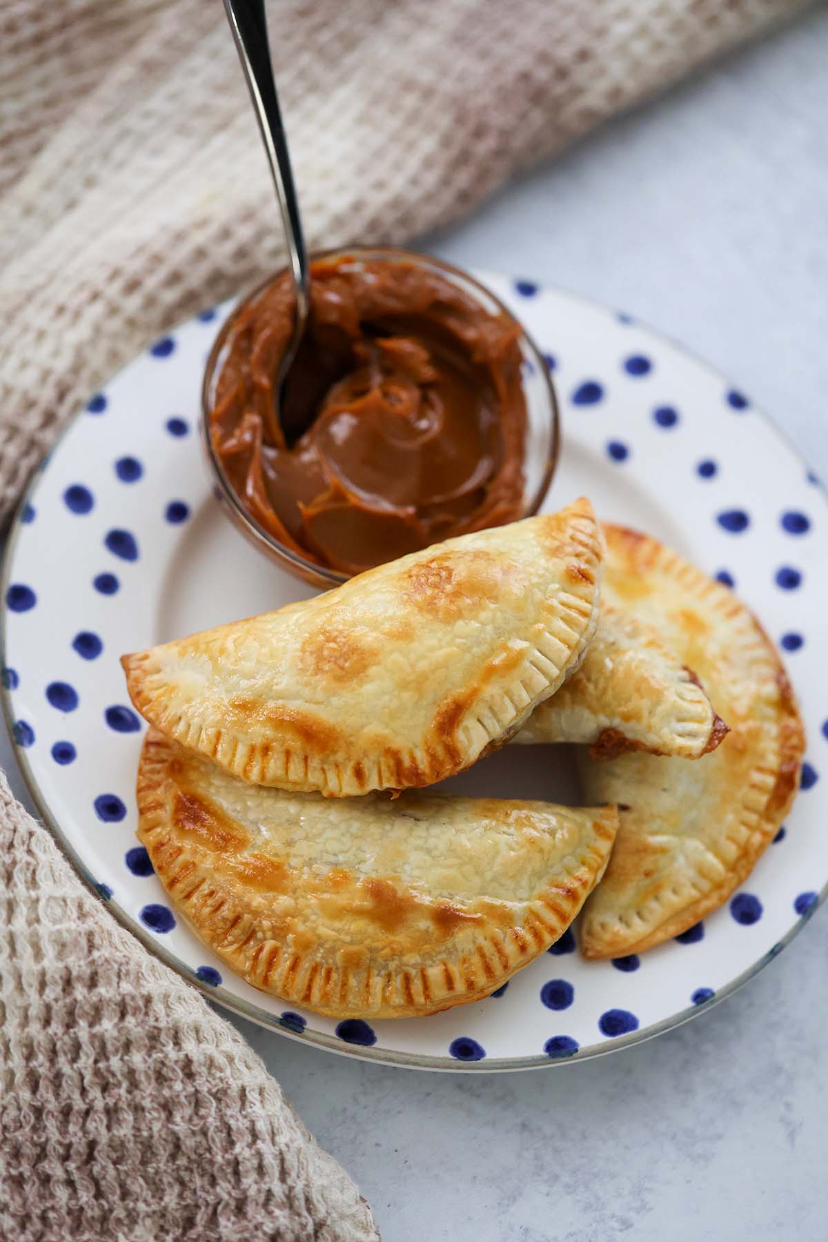 dulce de leche empanadas on a plate with dulce de leche on the side. 