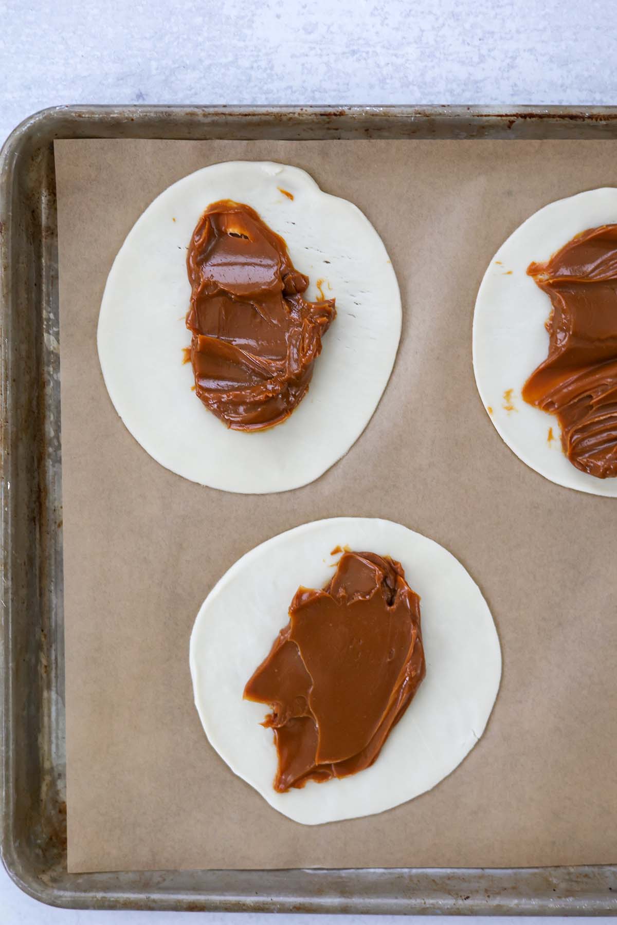 dulce de leche smeared on empanada discs. 