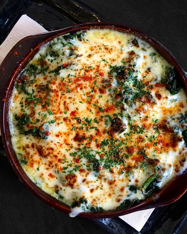 keto spinach dip with melted cheese and parsley on top.