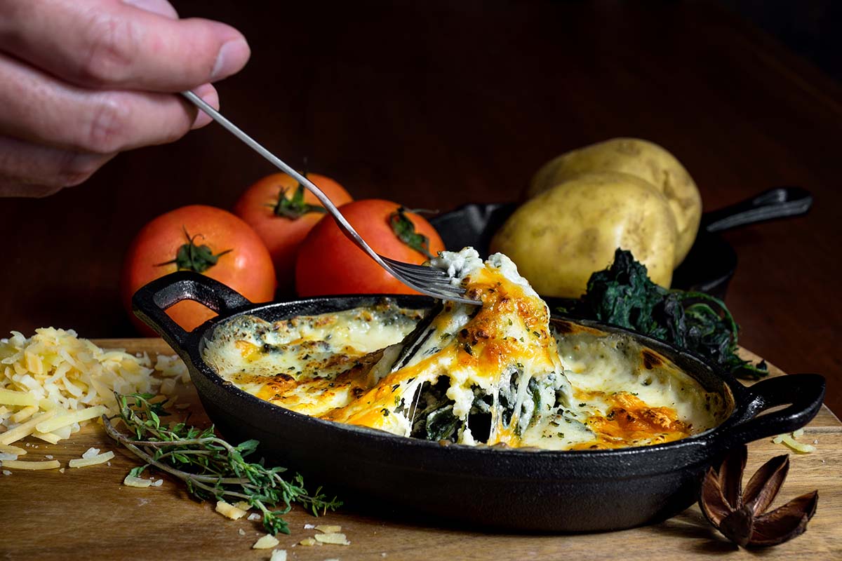 fork lifting spinach dip out of baking dish.