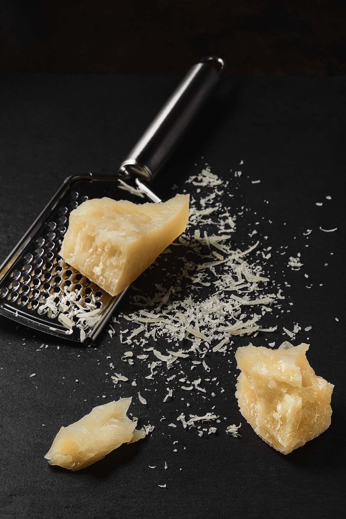 blocks of parmesan cheese with a cheese grater on the side. 