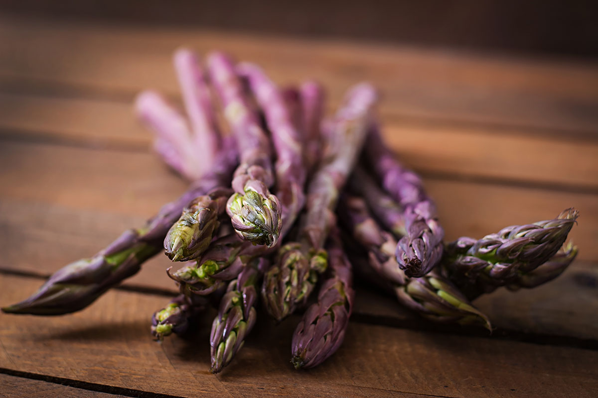 purple asparagus on a wooden board.