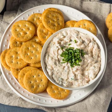 smoked salmon dip with chives on top and crackers on the side.