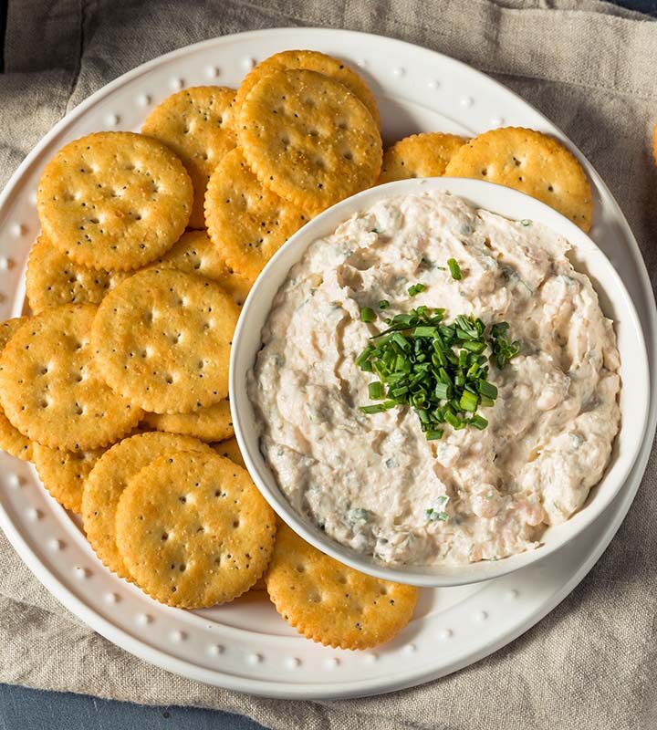 smoked salmon dip with chives on top and crackers on the side.