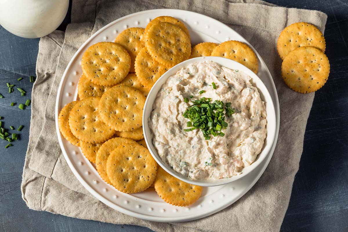 smoked salmon dip with chives on top and crackers on the side. 