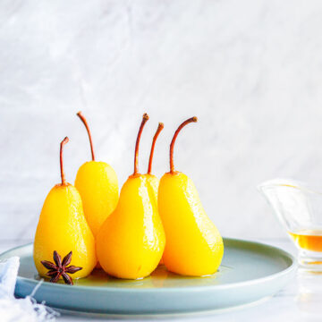 five glazed pears on a plate.