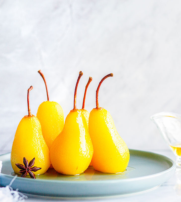 five glazed pears on a plate.