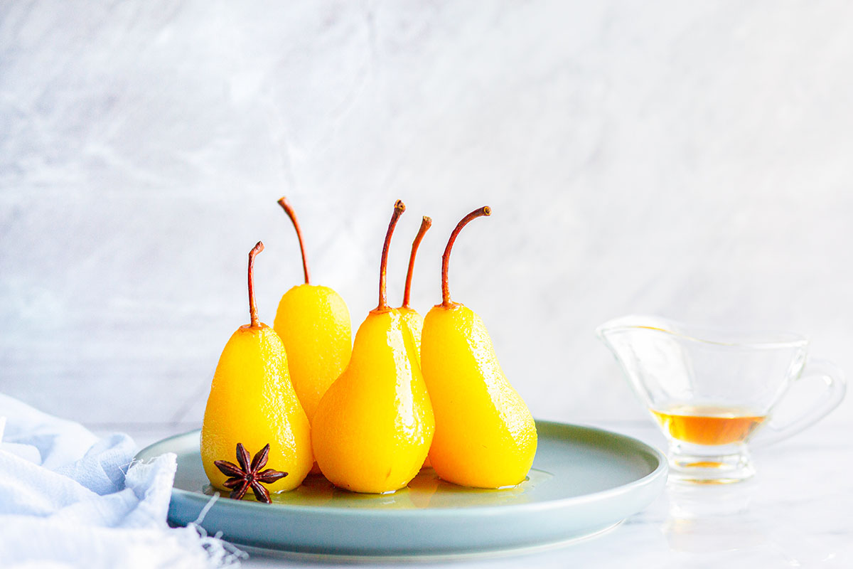 five glazed pears on a plate. 