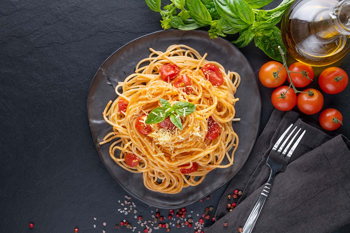 vegetarian spaghetti with tomatoes, basil, and oil on the side.
