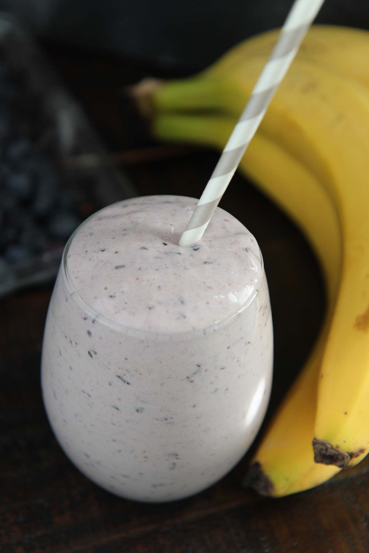 blueberry banana protein smoothie with a straw.