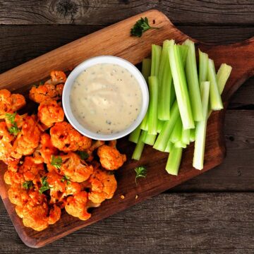 buffalo cauliflower with blue cheese dip and celery sticks on the side.