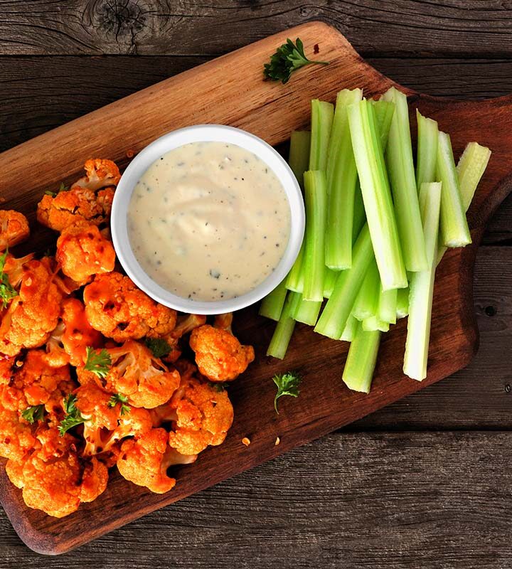 buffalo cauliflower with blue cheese dip and celery sticks on the side.