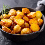 canned potatoes in a skillet with rosemary on the side.