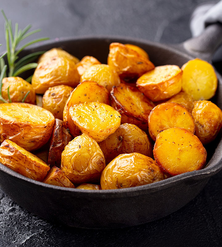 canned potatoes in a skillet with rosemary on the side.