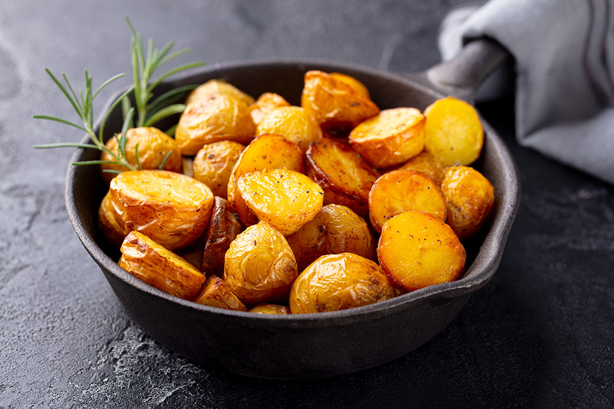 canned potatoes in a skillet with rosemary on the side.