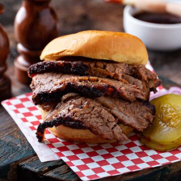 Traeger brisket sandwich with pickles and onions on the side.