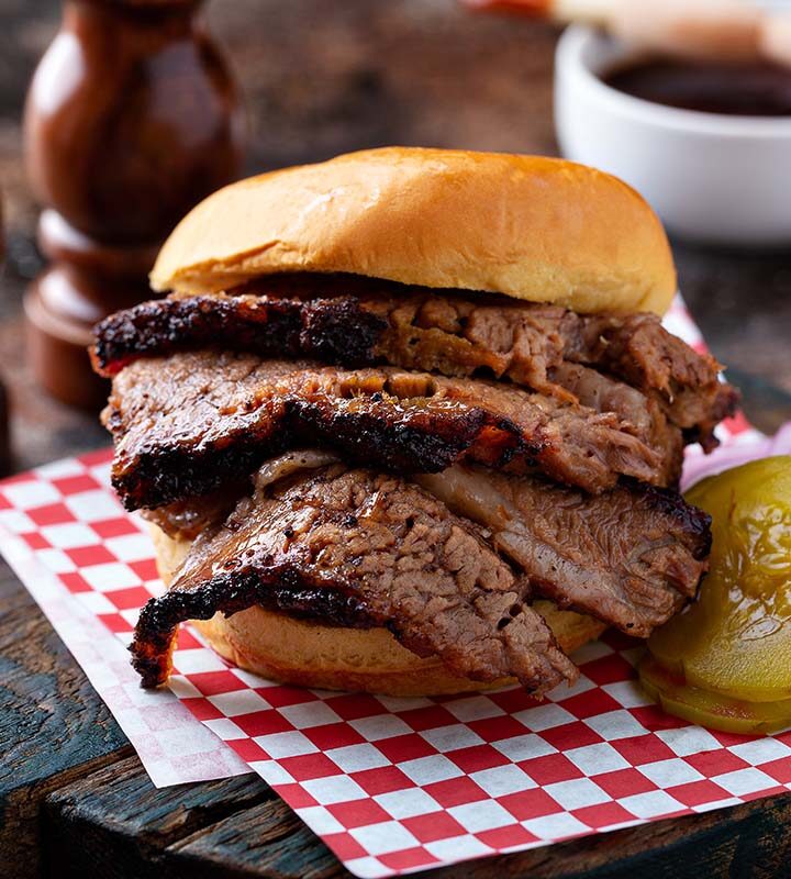 Traeger brisket sandwich with pickles and onions on the side.